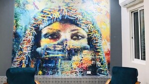 Une pièce avec un plafond recouvert de carreaux, deux chaises en bois et un grand tableau abstrait accroché au mur.