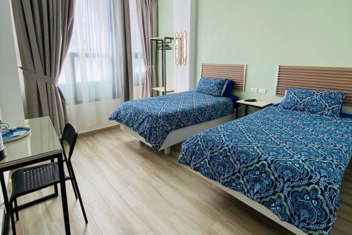 A room with two beds, a table, and a chair.