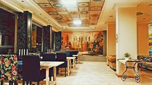 Un restaurant doté d’un long comptoir, de plusieurs tables et d’une fresque murale sur le mur du fond.
