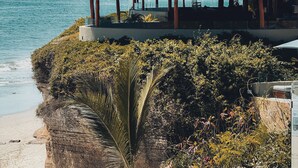 Une propriété située en bord de mer, dotée d’une structure au toit de chaume et offrant une vue sur l’océan.