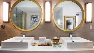 A bathroom with two sinks, each with a round mirror and a light above. There are toiletries on the counter.