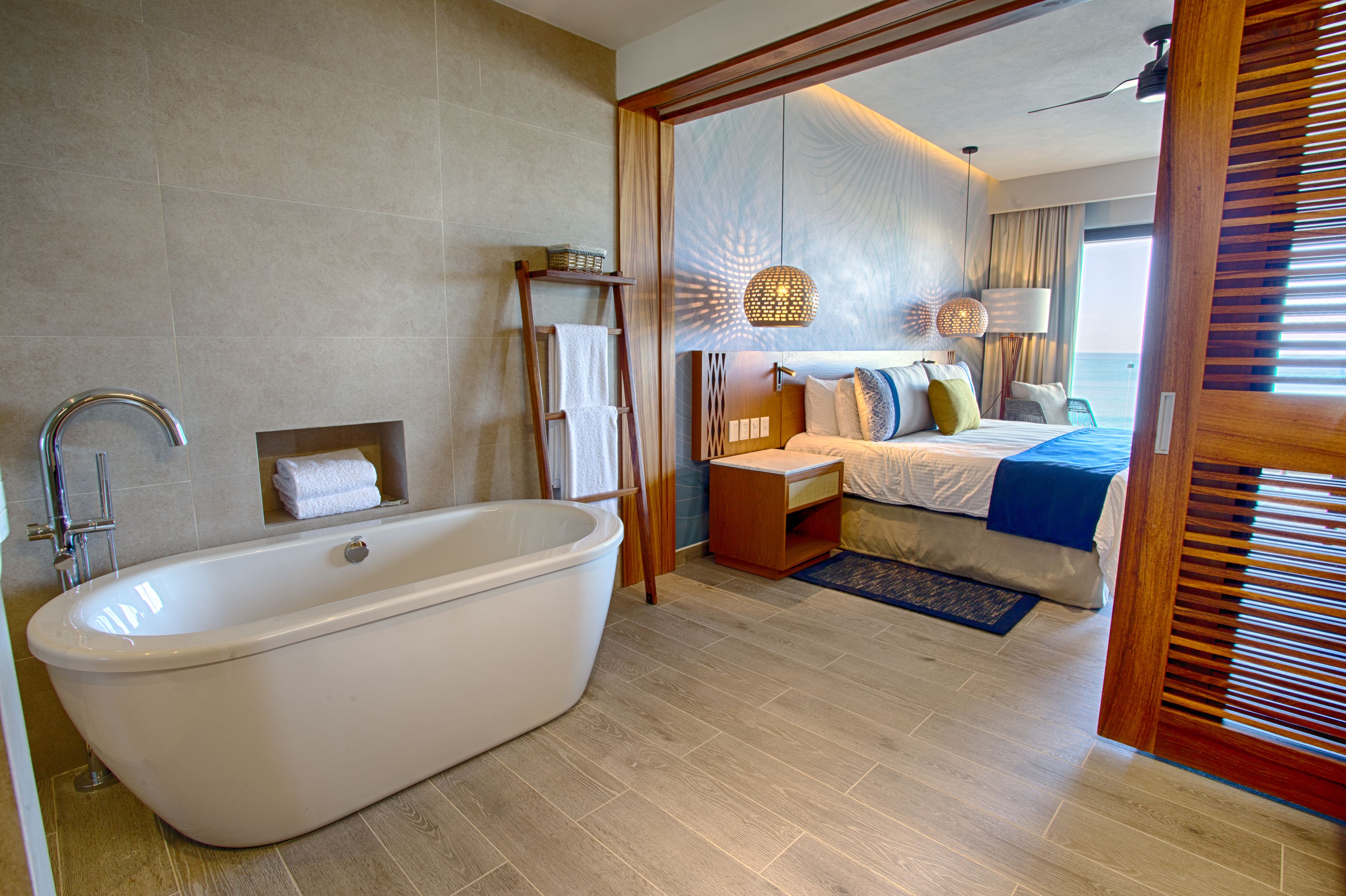 Un baño moderno con una bañera independiente, un tocador de madera y un perchero para toallas.