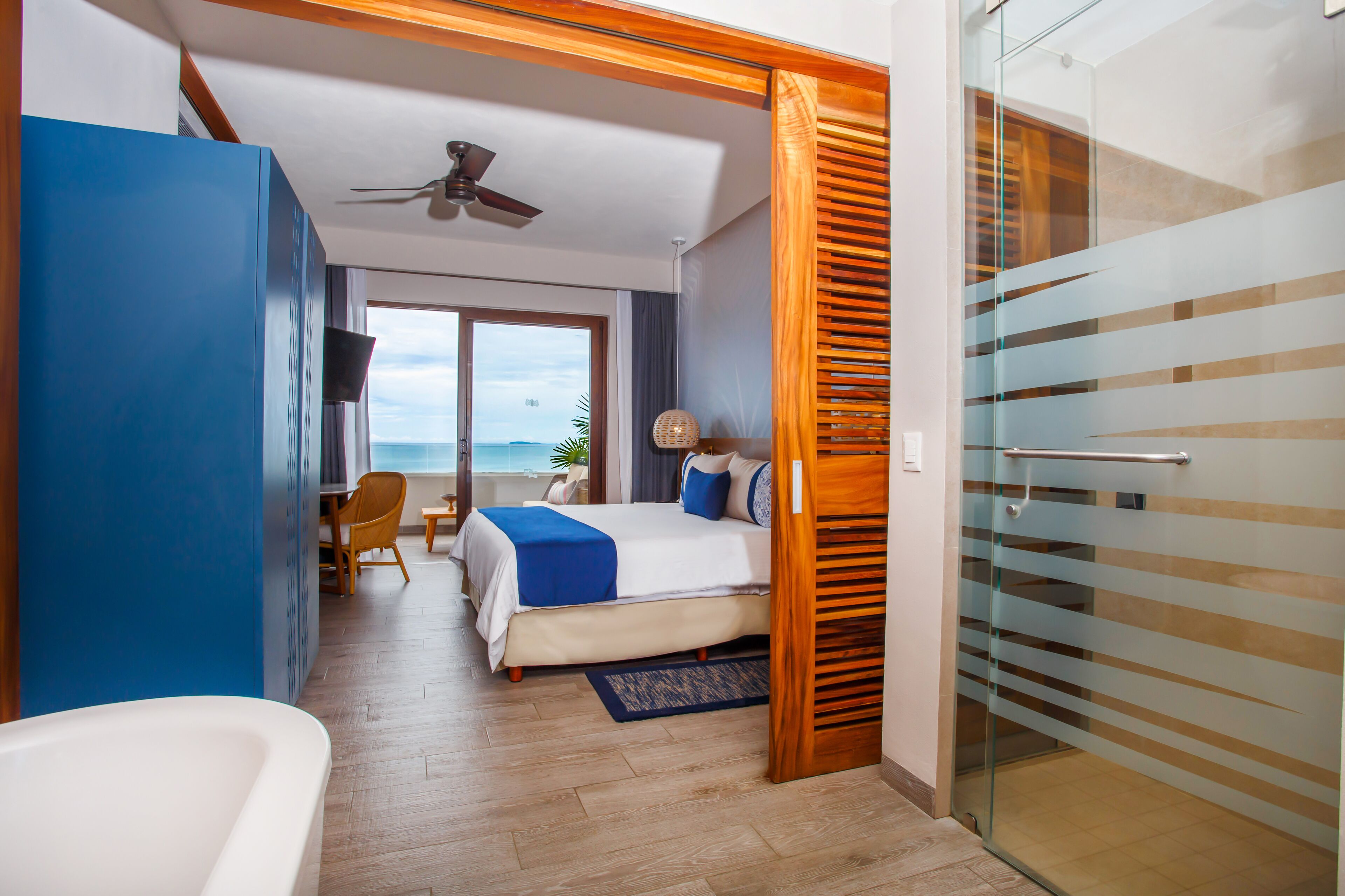 Habitación de hotel moderna con una cama, un escritorio y vista al mar.