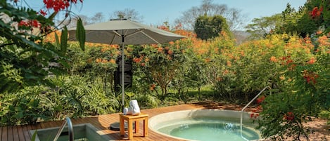 A hot tub surrounded by lush greenery and a wooden deck.