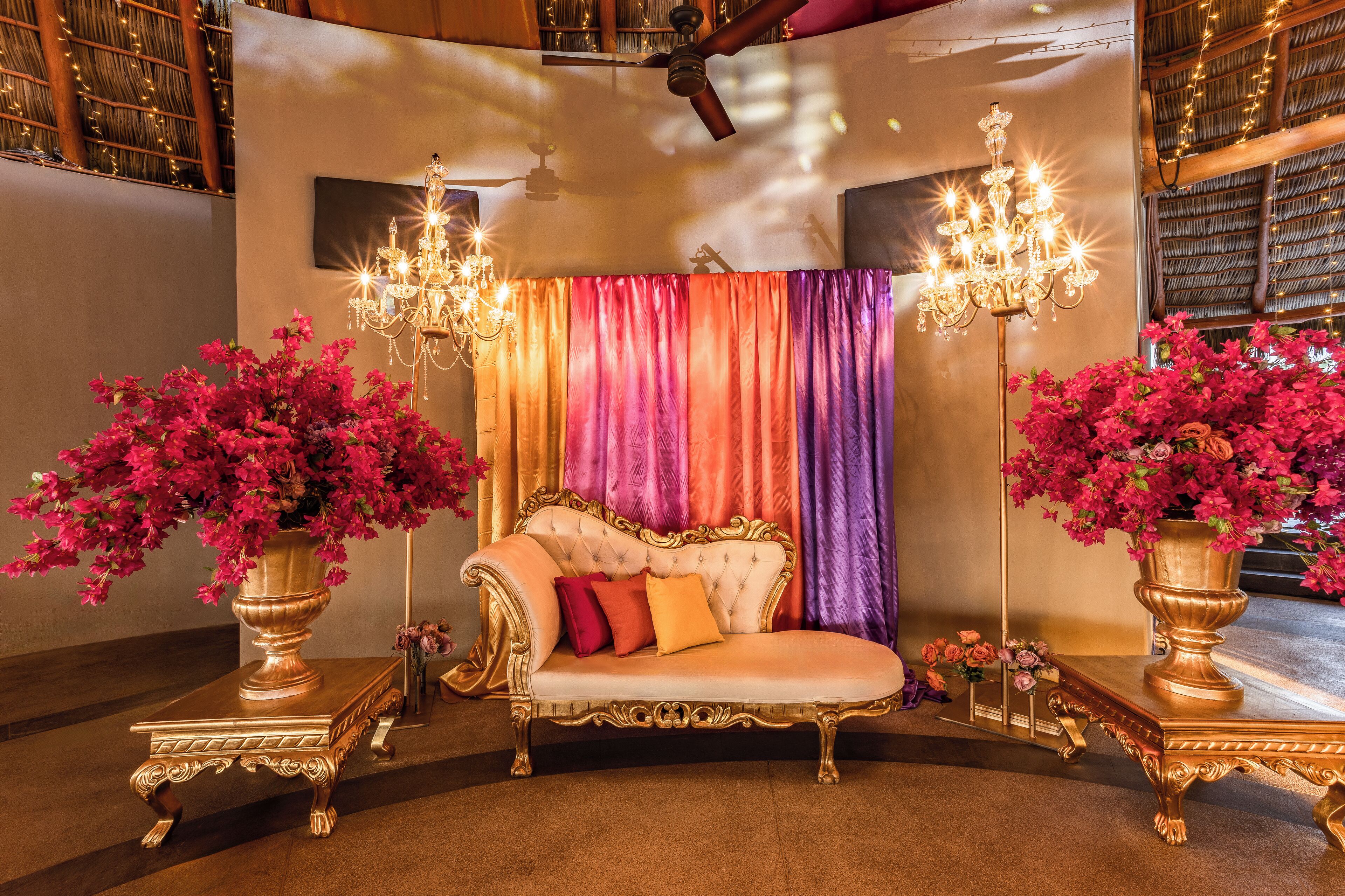 Een luxe kamer met een comfortabele bank, versierde kroonluchters en levendige gordijnen.