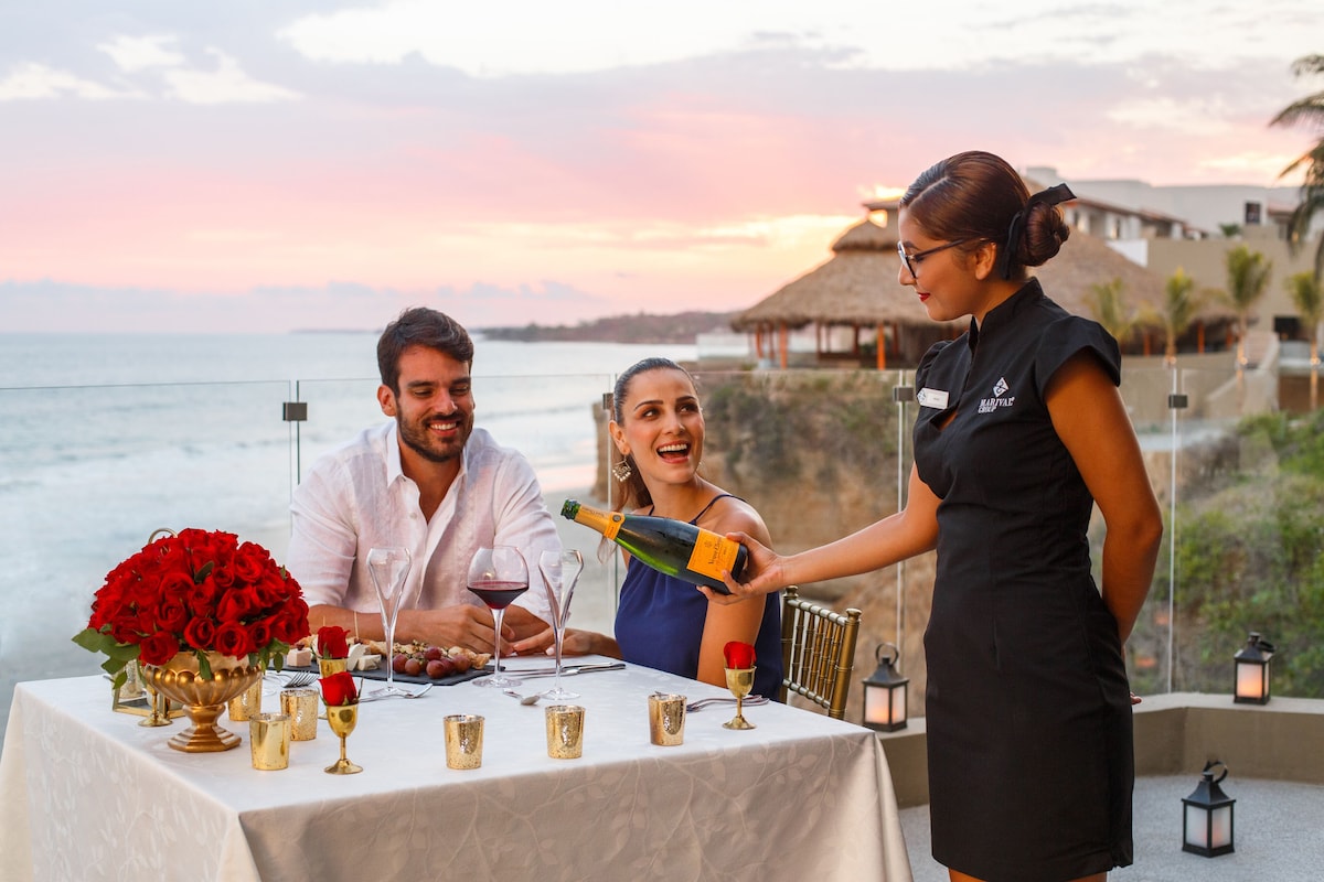 woman pouring wine for two guests who are dining at Marival Armony All Inclusive Resort in Mexico