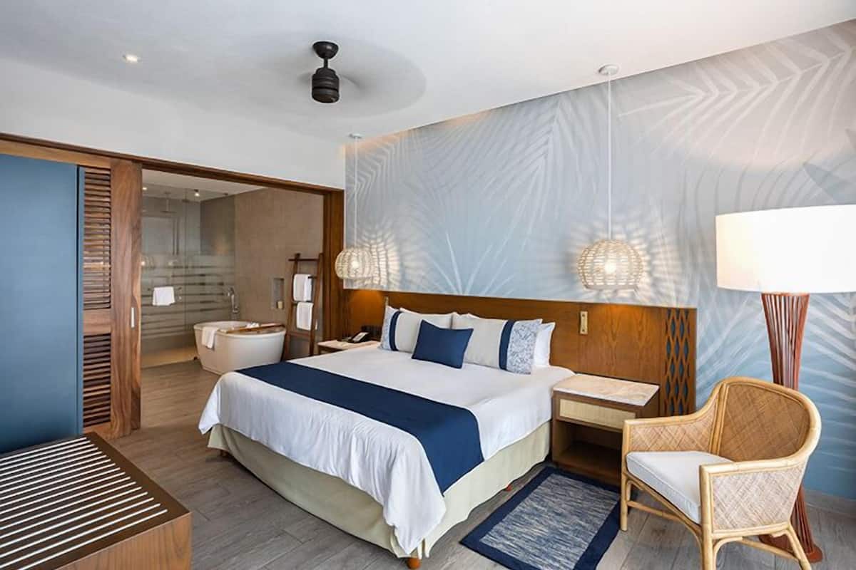 Een moderne hotelkamer met een groot bed, nachtkastjes, een bureau, een stoel, een badkamer en een douche.