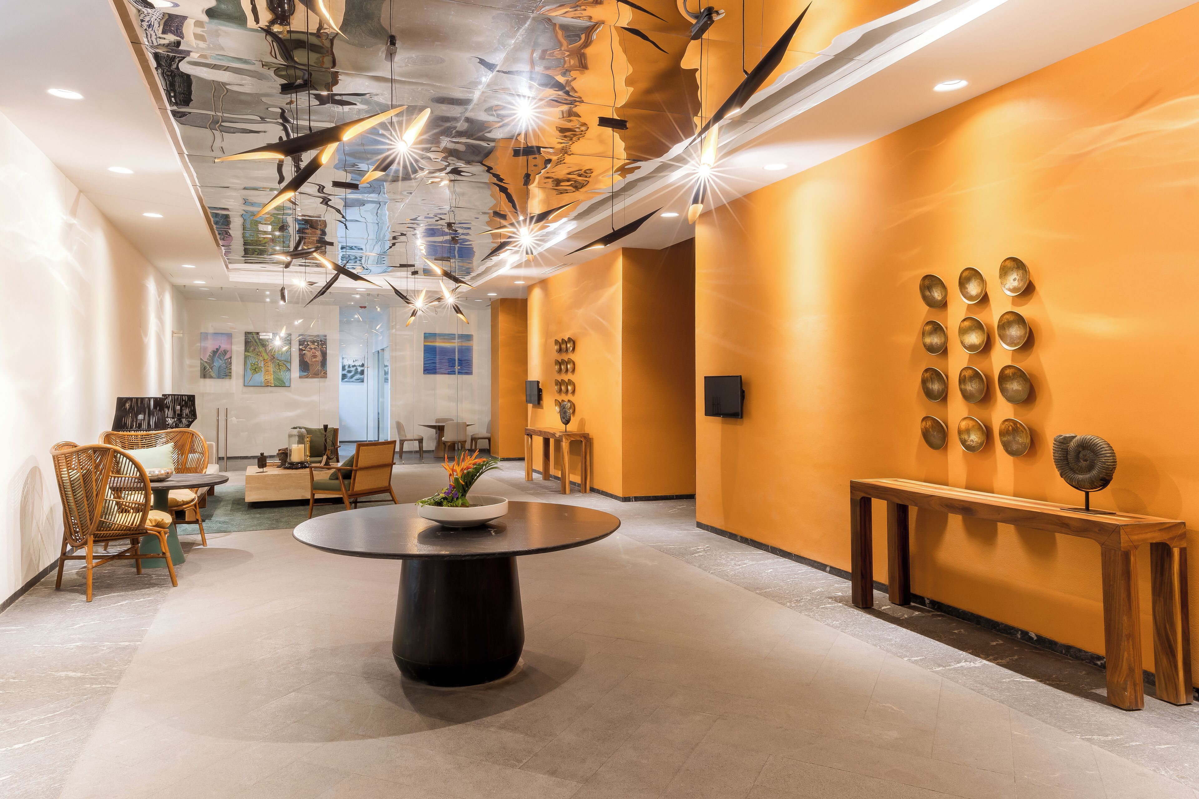 A modern lobby with a round table, seating area, and decorative wall art.