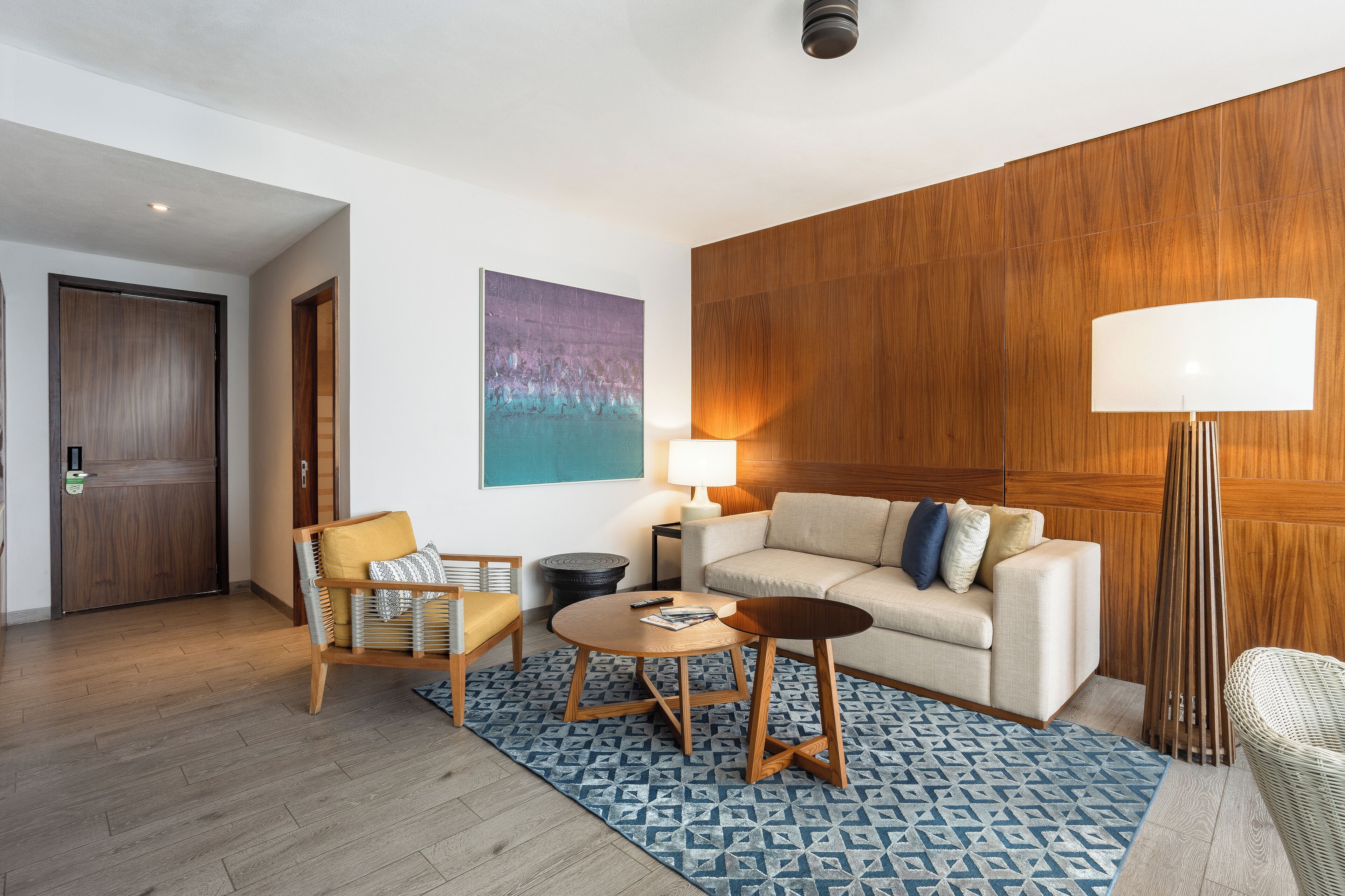 Una sala de estar moderna con sofá, sillón, mesa de centro y lámpara.