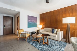 Una sala de estar moderna con sofá, sillón, mesa de centro y lámpara.