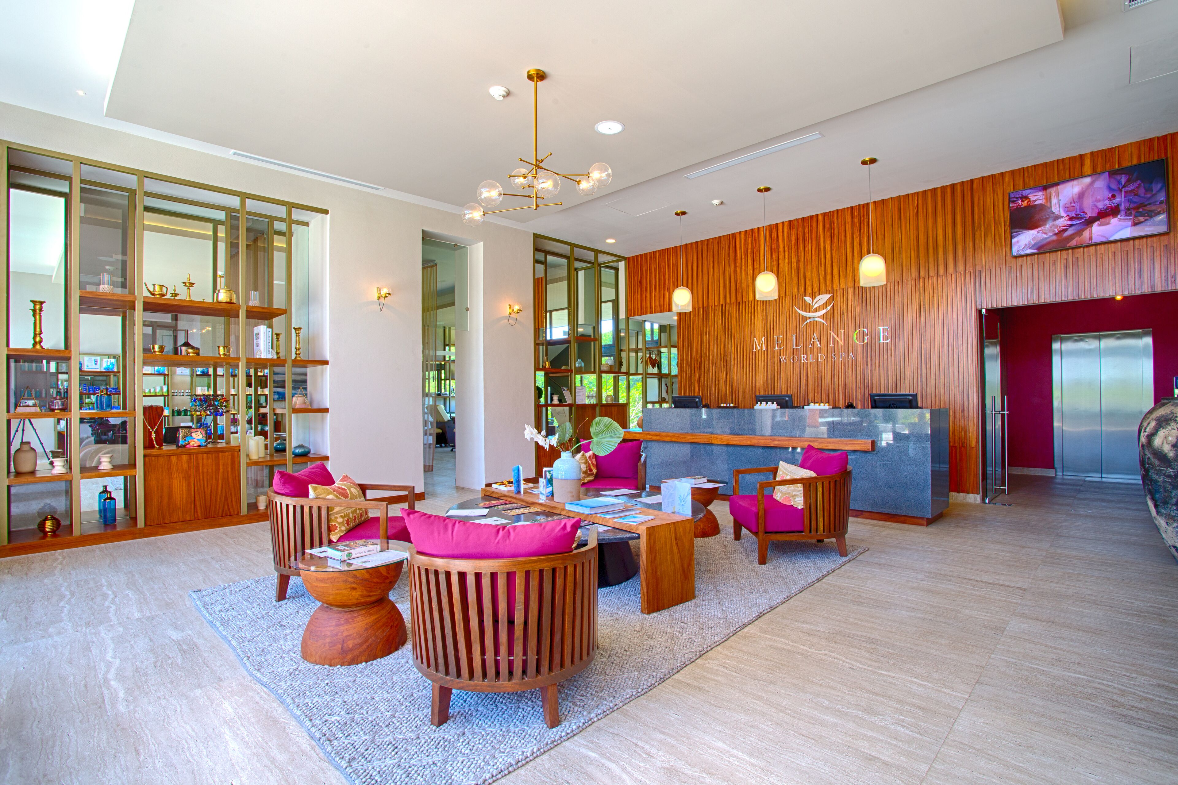 Een moderne hotellobby met een receptiebalie, een zithoek en een groot raam met uitzicht op de omgeving.