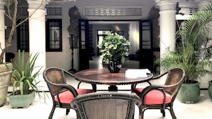 A traditional-style dining area with a round table and wicker chairs, surrounded by potted plants. - Orchard House (Galle)