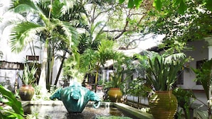 A courtyard with a fountain, potted plants, and a building in the background. - Orchard House (Galle)