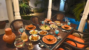 A dining table set with various dishes, glasses, and a pool in the background. - Orchard House (Galle)