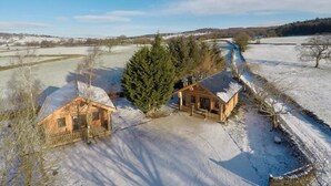 A wooden cabin with a snow-covered landscape, surrounded by trees and a river. - Braisty Woods - Knotty & Nice (Harrogate)