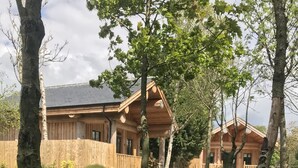 A wooden cabin with a porch, surrounded by trees and a grassy yard. - Braisty Woods - Knotty & Nice (Harrogate)