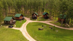A lodge with multiple cabins, a central dirt road, and surrounding forest.