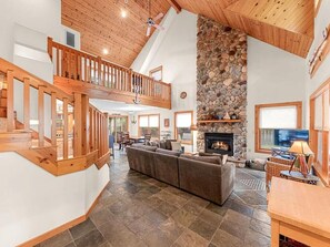 A spacious living area with a stone fireplace, wooden ceiling, and a large sofa. - Private Setting Union Pier - Walk to Beach, Shops & Restaurants | Anchor Point (Union Pier)