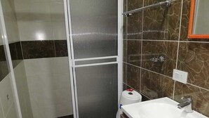 Une salle de bain avec une douche, des toilettes et un lavabo.