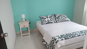 Une chambre à coucher avec un lit, une table de chevet avec une lampe et une porte.