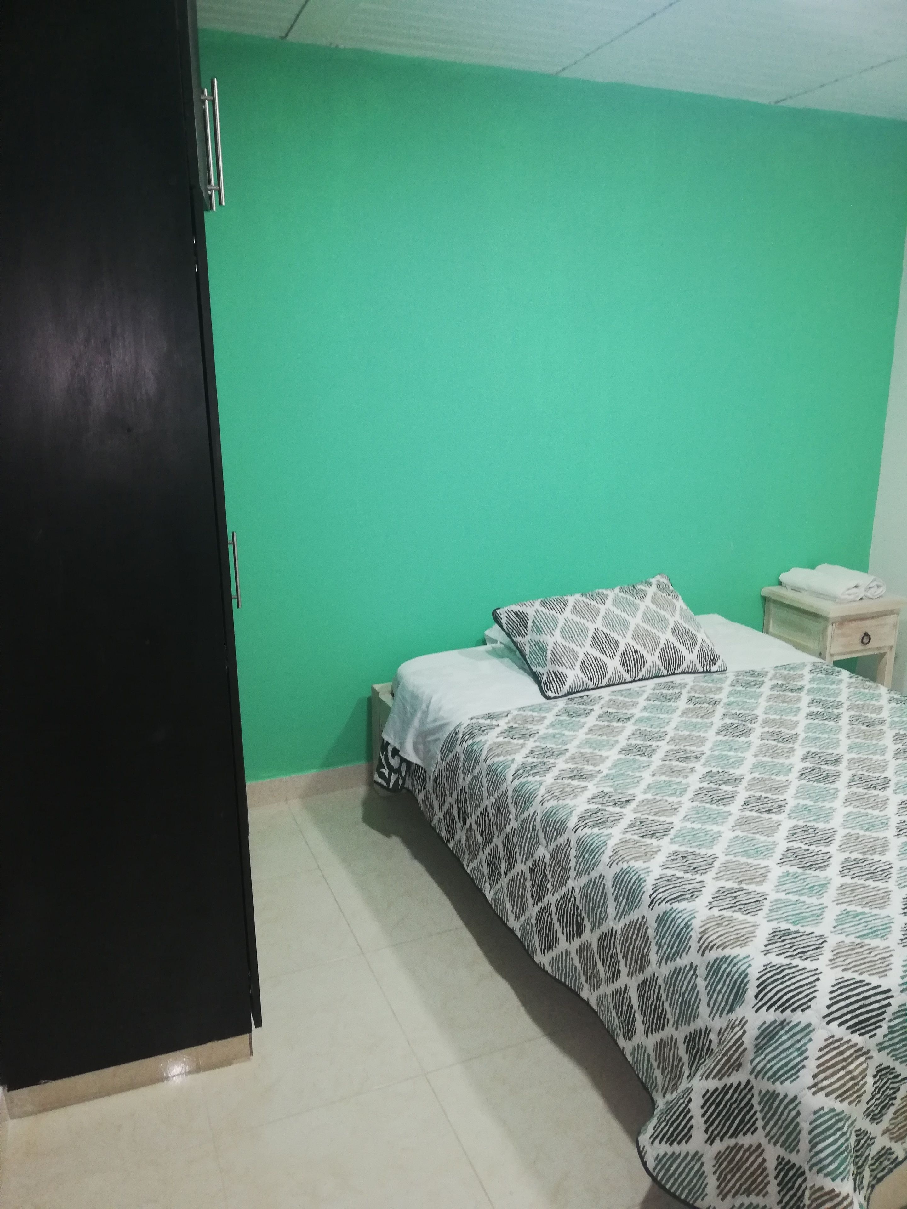 Een slaapkamer met een bed, nachtkastje en garderobe.