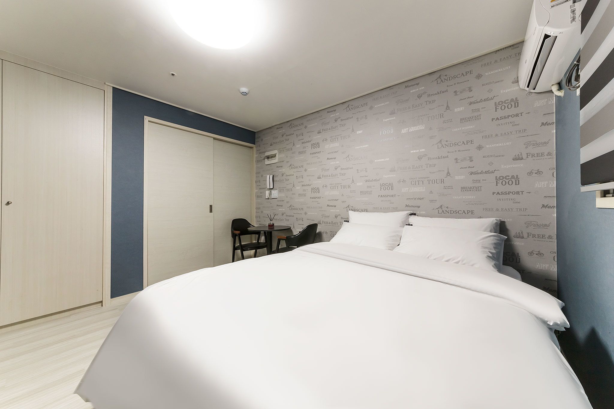 Habitación de hotel con cama, escritorio y silla. Incluye armario y equipo de aire acondicionado.