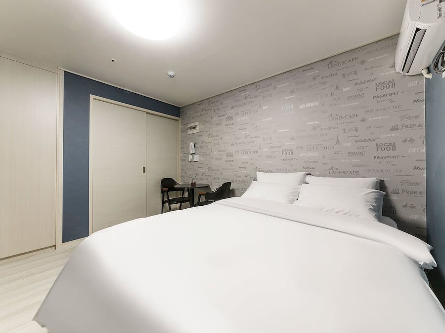 Habitación de hotel con cama, escritorio y silla. Incluye armario y equipo de aire acondicionado.