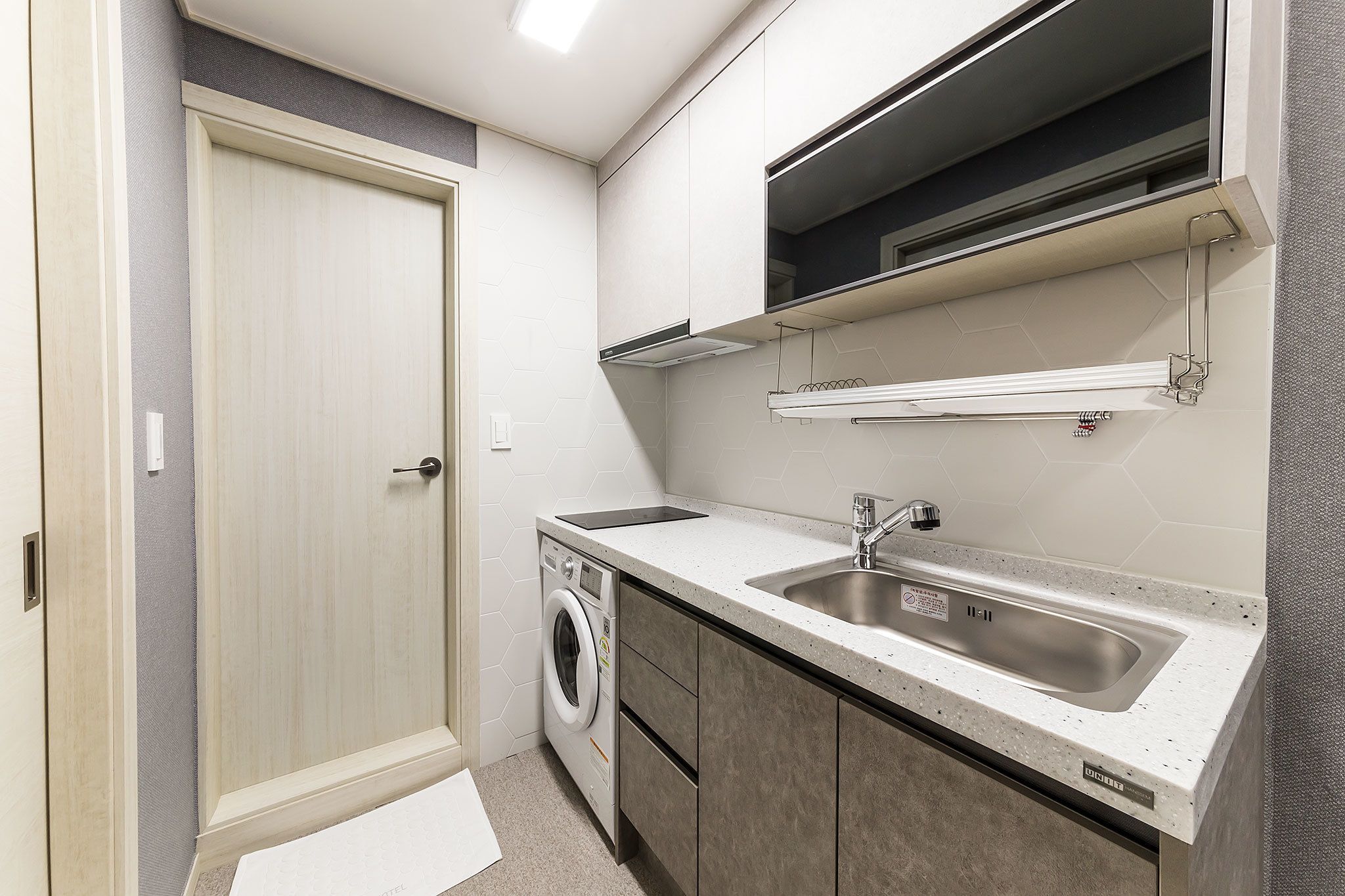 A compact kitchen with a built-in washing machine, a sink, and cabinets.
