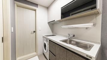 A compact kitchen with a built-in washing machine, a sink, and cabinets.