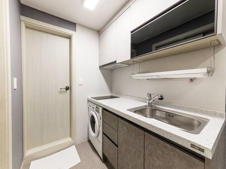 A compact kitchen with a built-in washing machine, a sink, and cabinets.