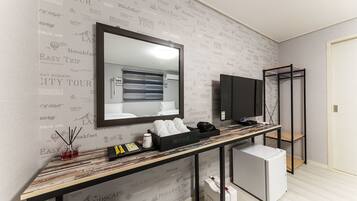 A hotel room with a large mirror, a television, a minibar, and a small refrigerator.