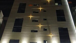 Une enseigne d’hôtel avec des lettres lumineuses qui épellent « HOTEL It’s W », et une enseigne de café en dessous.