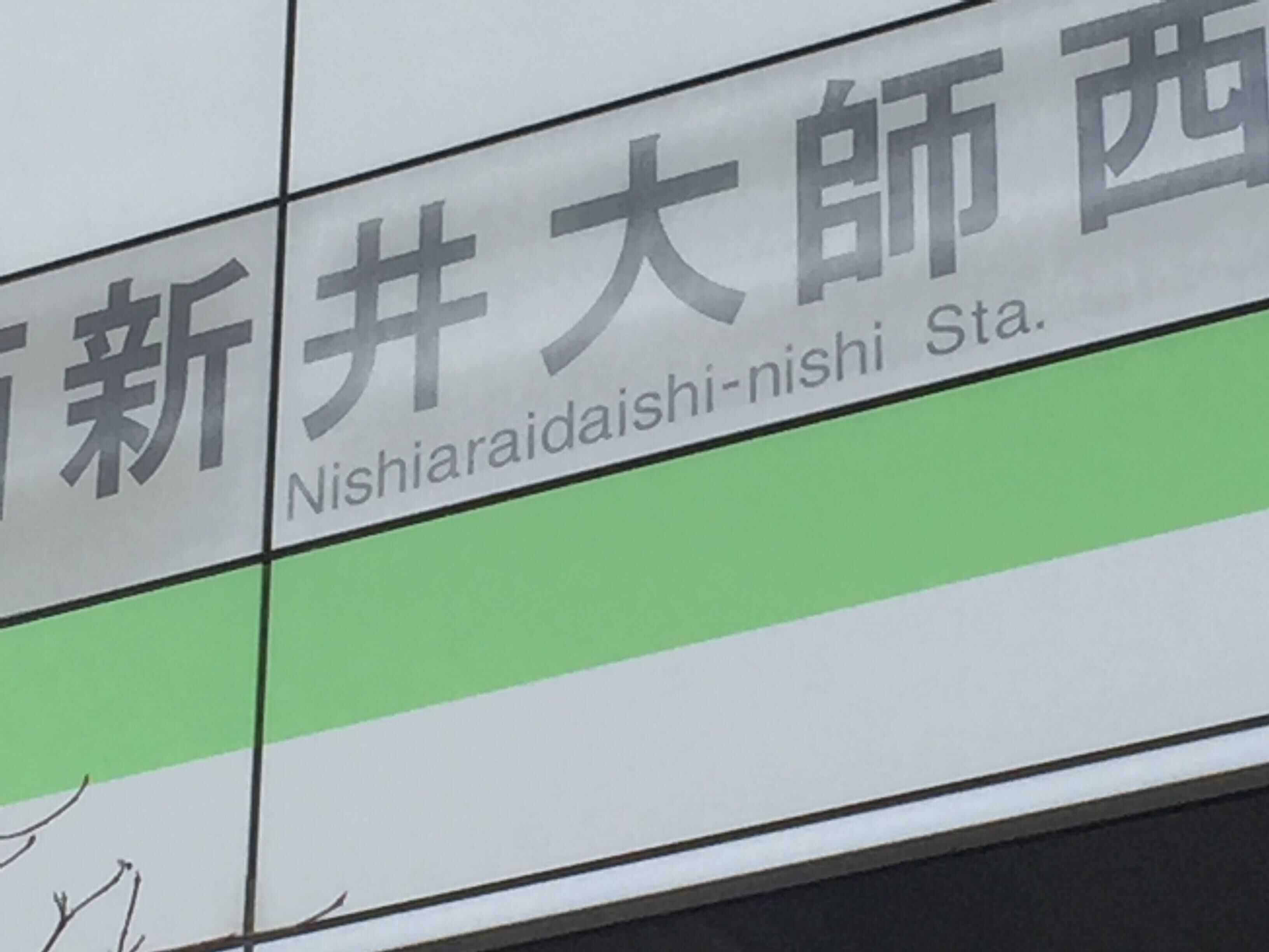 A sign with Japanese characters and the English translation "Nishiarai-daiishi-nishi Sta."