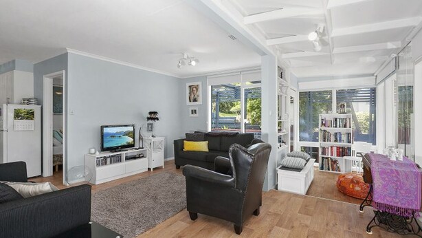 Ein modernes Wohnzimmer mit Flachbildfernseher, einer Couch, einem Couchtisch und einem Bücherregal.