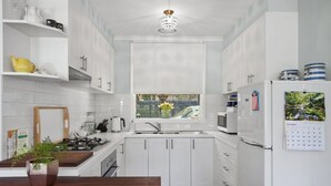 Eine moderne Küche mit weißen Schränken, einer Holz Arbeitsplatte, einem Herd, einer Spüle und einem Kühlschrank.