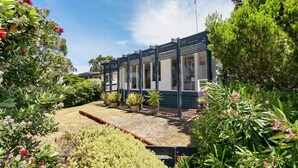 Uma casa moderna com varanda coberta, rodeada por vegetação exuberante e plantas floridas.