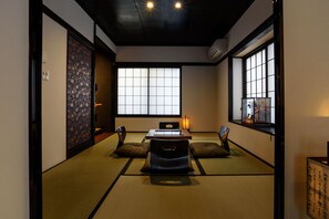 Experience traditional Japanese elegance in this serene room featuring tatami flooring, a low table, and a window with a view.