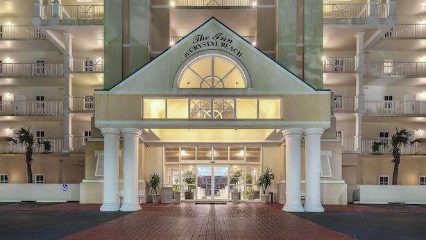 A hotel entrance with a sign reading "The Inn at Crystal Beach," featuring a symmetrical facade with columns, balconies, and potted plants.