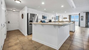 A spacious kitchen with white cabinetry, a central island, and a stainless steel refrigerator.