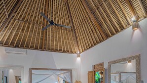 A spacious room with a large bed, a wooden ceiling, and a dining area with a table and chairs. - Charming Tropical Villa for Couple and Honeymooner (Gianyar)