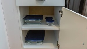A kitchen cabinet with three shelves, each holding a glass container with a blue lid.