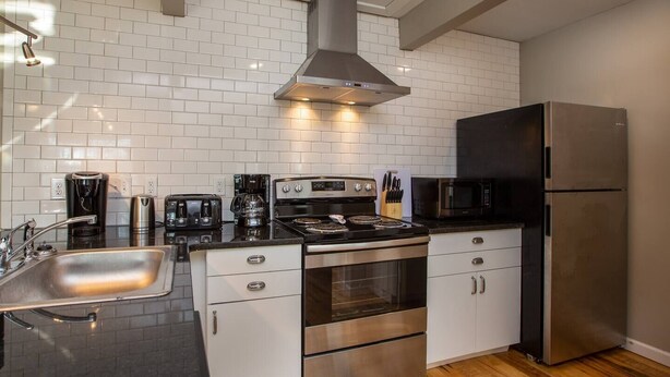A modern kitchen with white subway tiles, stainless steel appliances, and a black refrigerator.
