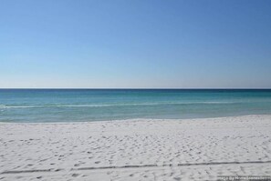 A beach with white sand and calm blue water.