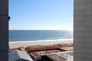 Uitzicht op een strand met een heldere lucht, een zandstrand en een gebouw met een rood dak op de voorgrond.