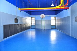 Een binnenshuis basketbalveld met een blauwe vloer, een basketbalring en een bord met de tekst 'NO DUNKING'.