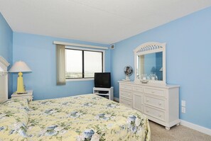 Una camera da letto con un letto, una cassettiera, una televisione, una finestra e uno specchio.