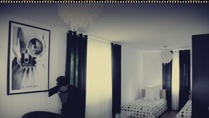 Une chambre d’hôtel avec un lit, une chaise, une petite table et un tableau encadré au mur.