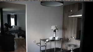Une cuisine moderne avec un plan de travail noir, une étagère en métal ornée de fleurs blanches et des armoires en bois.