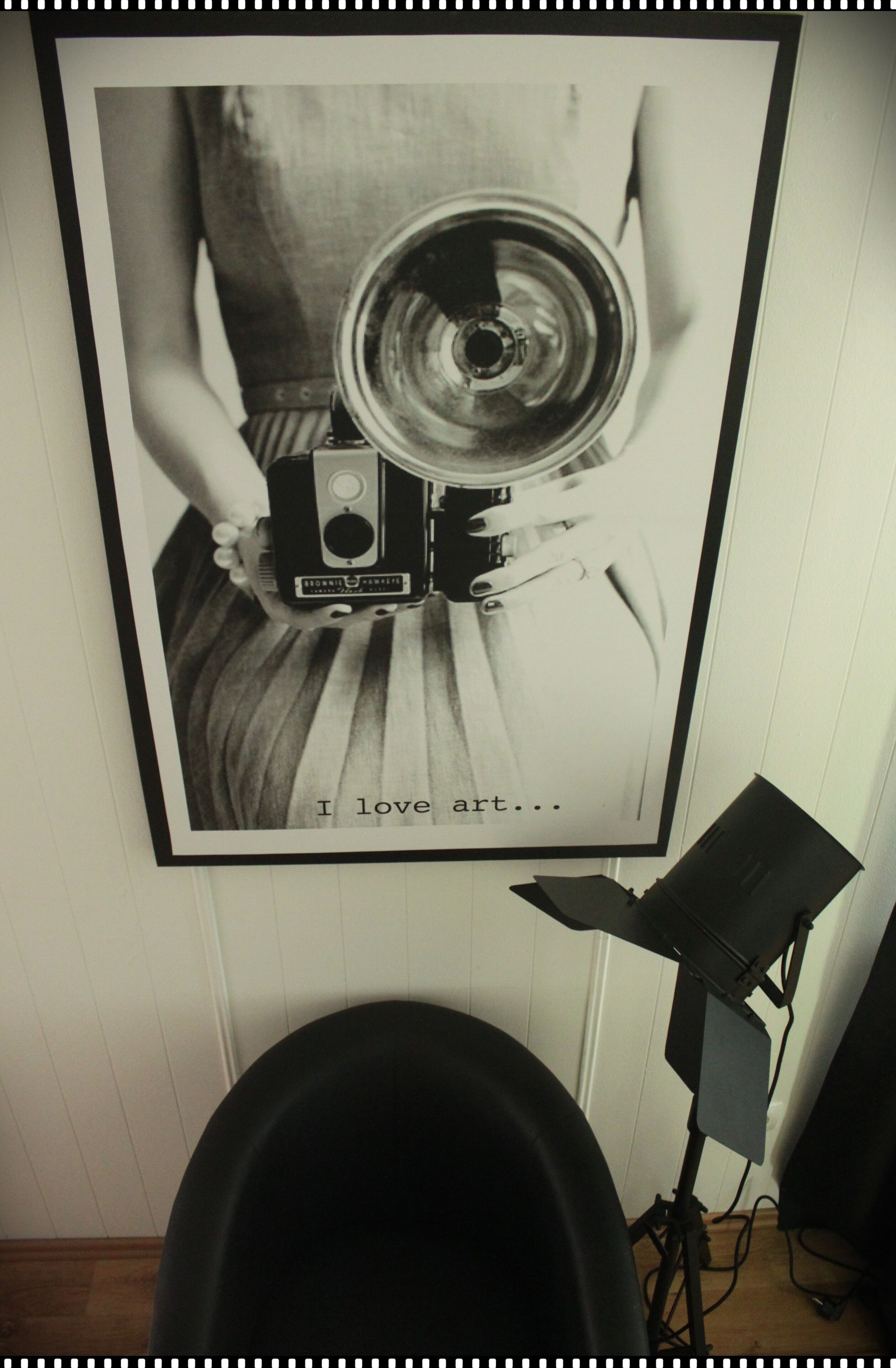 A framed photograph of a vintage camera on a person's hand, with the text "I love art..." below it.