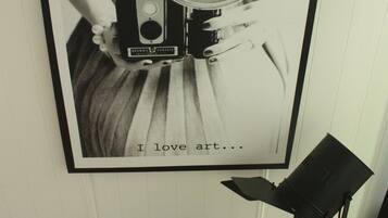 A framed photograph of a vintage camera on a person's hand, with the text "I love art..." below it.